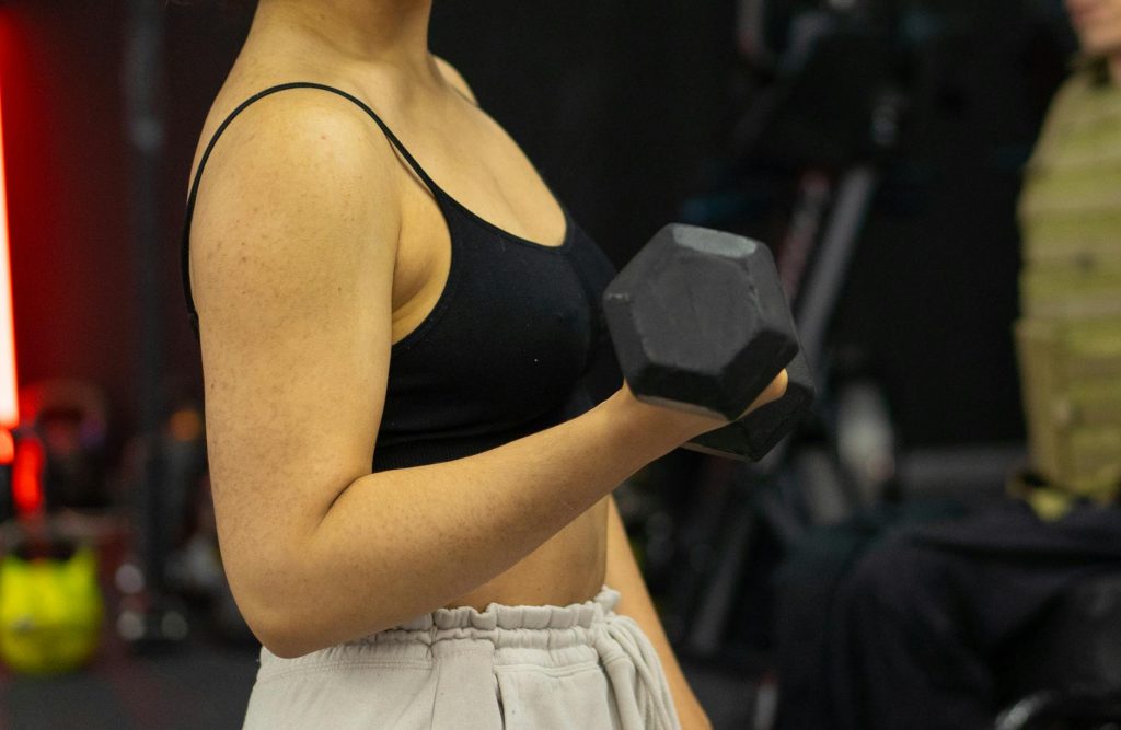 a woman in black crop top lifting a dumbbell